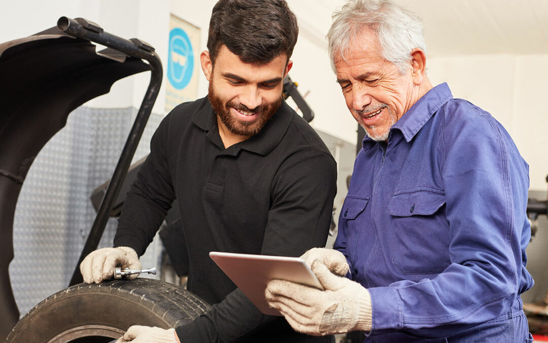 Zwei Männer in der KFZ-Werkstatt schauen auf ein Tablet